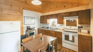 a kitchen with a table and a white refrigerator at Affordable cabin that sleeps 8 K beds & fire pit in Cosby