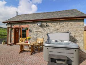 a hot tub sitting outside of a stone house at Tegfan Barn in Pant-y-dwr
