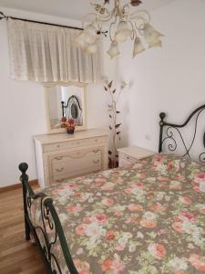 - une chambre avec un lit et une commode avec une couverture fleurie dans l'établissement Vista lago panoramica, à Colonno