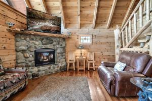 een woonkamer met een stenen open haard in een blokhut bij Alpine Rose Beautiful Cabin Hot Tub Mountain Views in Sevierville