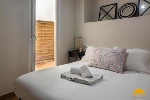 Una cama blanca con toallas encima. en Writer's Home by Cadiz Time, en Cádiz