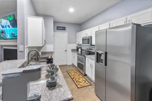 a kitchen with a stainless steel refrigerator and white cabinets at Roanoke Hidden Oasis Resort Style Living in Roanoke