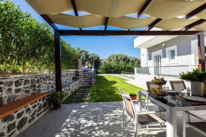 a patio with a table and chairs and a wall at Villa Emily Rethymno in Adelianos Kampos