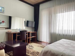 Habitación de hotel con cama y escritorio en Ladera Resort Qusar, en Qusar