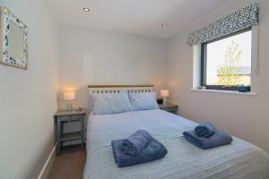 um quarto com uma cama com toalhas azuis em Luxury property with access into Spa on a nature reserve Beaumont Village 5 BV05 em Warmwell