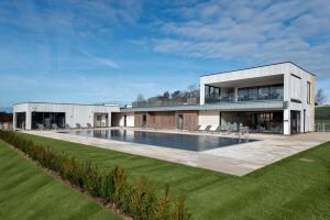 uma casa grande com uma piscina em frente em Luxury property with access into Spa on a nature reserve Beaumont Village 5 BV05 em Warmwell