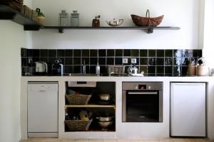 una cocina con armarios blancos y azulejos negros en la pared en La Suite de la Bastide, en Val-de-Dagne
