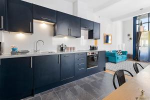a kitchen with dark blue cabinets and a table at Smythen St, 2 bed apartment with balcony in Exeter