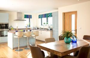 a kitchen and dining room with a wooden table and chairs at Lakeside property with spa access on a nature reserve Rainbows BV17 in Warmwell