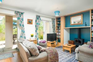 ein Wohnzimmer mit einem Sofa und einem TV in der Unterkunft Lakeside property with access into Spa on a nature reserve Bee Cottage HM75 in Somerford Keynes