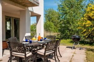 a patio with a table and chairs and a grill at Lakeside property with access into Spa on a nature reserve Bee Cottage HM75 in Somerford Keynes