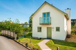 une maison blanche avec un balcon dans une rue dans l'établissement Lakeside property with access into Spa on a nature reserve Bee Cottage HM75, à Somerford Keynes