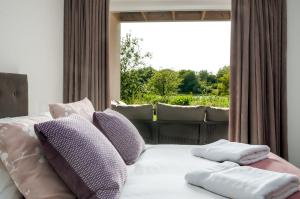 a bedroom with a bed with pillows and a window at Luxury apartment with spa access on a nature reserve Dragonfly HM106 in Somerford Keynes