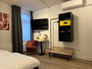 a hotel room with a bed and a desk and a tv at Zest Hotel Daalhemerweg in Valkenburg