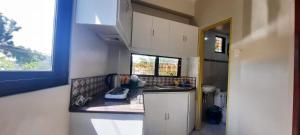 a small kitchen with white cabinets and a window at The Pine Place - Baguio in Baguio