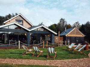 a group of lawn chairs in front of a house at Lakeside property with spa access on a nature reserve Keel House CW23 in Somerford Keynes