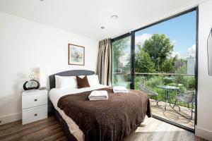 ein Schlafzimmer mit einem Bett und einem großen Fenster in der Unterkunft Lakeside roof terrace with Spa access Le Mirage in Somerford Keynes + 33 Fotos