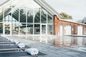 ein großes Glasgebäude mit Bänken davor in der Unterkunft Lakeside roof terrace with Spa access Le Mirage in Somerford Keynes