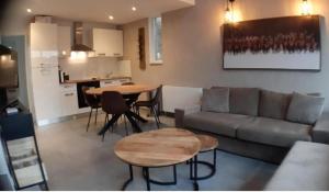 ein Wohnzimmer mit einem Sofa und Tischen sowie eine Küche in der Unterkunft Terrasses de Malmedy Lodge 417 in Malmedy