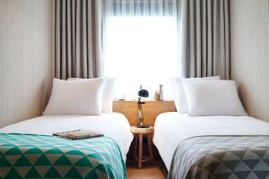 فندق جود لندن في لندن: سريرين في غرفة الفندق مع نافذة