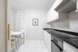 a white kitchen with a sink and a table at Paraguay 14 in Vigo