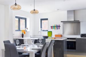 a white kitchen with a table and chairs at Lakeside property with spa access on a nature reserve Sunbird Cottage BV20 in Warmwell