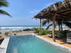 a swimming pool next to a beach with the ocean at Quinta Feliz Troncones in Troncones