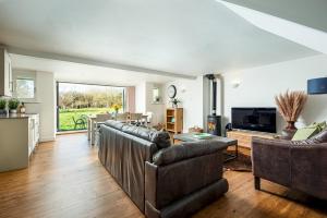 a living room with leather furniture and a large window at Lakeside property with spa access on a nature reserve Ruby Cottage MV04 in Somerford Keynes
