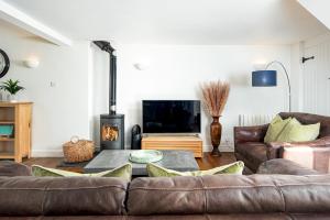 a living room with a couch and a tv at Lakeside property with spa access on a nature reserve Ruby Cottage MV04 in Somerford Keynes