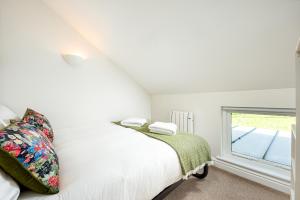 a white bedroom with a bed and a window at Lakeside property with spa access on a nature reserve Ruby Cottage MV04 in Somerford Keynes +9 photos
