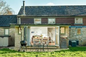 a patio with chairs and a grill in front of a house at Lakeside property with spa access on a nature reserve Ruby Cottage MV04 in Somerford Keynes