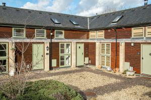 a brick house with green doors and windows at Lakeside property with spa access on a nature reserve Ruby Cottage MV04 in Somerford Keynes