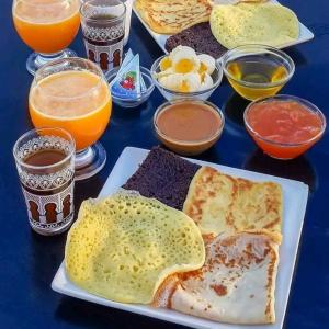 uma mesa com um prato de alimentos e bebidas ao pequeno-almoço em djou luxury desert camp em Merzouga