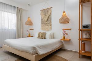 a bedroom with a large white bed and pendant lights at Terrasse Hotel Playa del Carmen in Playa del Carmen