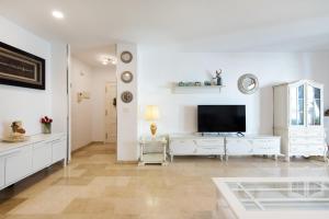 a white living room with a tv and a table at NEW ROYAL TORREQUEBRADA 2 Pets friendly & ideal for family groups in Benalmádena