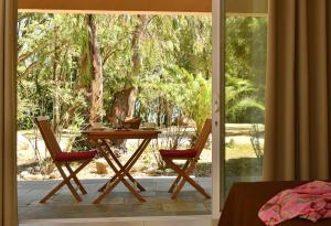 una mesa y 2 sillas frente a una puerta corredera de cristal en BAGHEERA Village Naturiste, en Linguizzetta