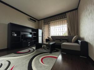 a living room with a couch and a television at Ladera Resort Qusar in Qusar