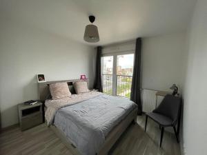 1 dormitorio con 1 cama, 1 silla y 1 ventana en Superbe appart avec vue panoramique sur La Défense, en Bois-Colombes