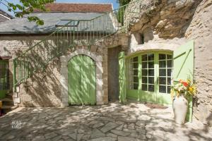 uma casa de pedra com uma porta verde e um vaso de flores em Songbird Sanctuary em Civray-de-Touraine