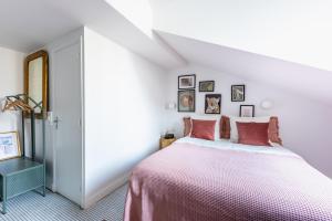 a white bedroom with a large bed with pink sheets at ROOM SAUVAGE in Vincennes