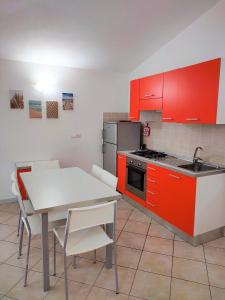 a kitchen with red cabinets and a table with chairs at Affittimoderni Santa Maria Coghinas in Santa Maria Coghinas