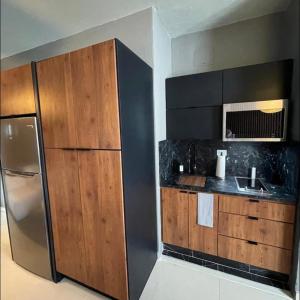 La cuisine est équipée d'un réfrigérateur en acier inoxydable et de placards en bois. dans l'établissement Moderno Apartamento para parejas San Juan Puerto Rico, à San Juan