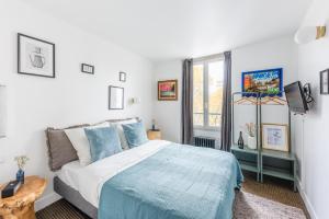 a bedroom with a bed with blue sheets and a window at ROOM SAUVAGE in Vincennes