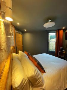 een slaapkamer met een bed met witte lakens en kussens bij Lough Rooms at The Artisan in Strangford