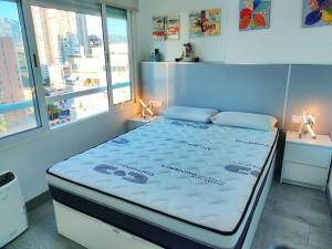 duże łóżko w pokoju z 2 oknami w obiekcie Bermudas apartamento con piscina y garaje en Benidorm w mieście Benidorm
