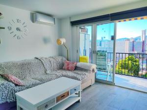 salon z kanapą i dużym oknem w obiekcie Bermudas apartamento con piscina y garaje en Benidorm w mieście Benidorm