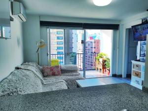 salon z kanapą i dużym oknem w obiekcie Bermudas apartamento con piscina y garaje en Benidorm w mieście Benidorm