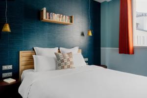 - une chambre avec un lit blanc et un mur bleu dans l'établissement Edgar Suites Expo Paris Porte de Versailles, à Paris