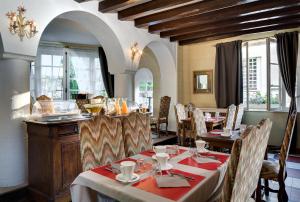 a dining room with tables and chairs and windows at Hotel La Roseraie in Chenonceaux