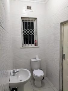 a white bathroom with a toilet and a sink at Inkanyezi Guest house in Durban